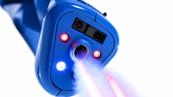 Krupni plan plave robotske glave s dvostrukim objektivima kamere i crvenim LED svjetlima, koja emitira ružičastu lasersku zraku iz središnjeg priključka.