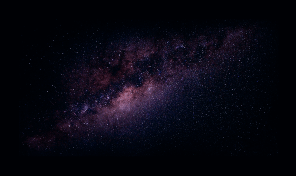 Vedere largă a galaxiei Calea Lactee ca o bandă roz prăfuită pe un cer întunecat și înstelat.