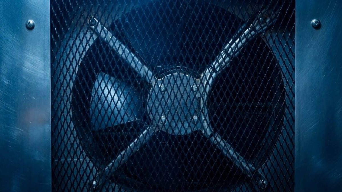 Industrielüfter hinter einem blauen Metallgitter in einem blau getönten Gehäuse, der Belüftungsanlagen transportiert