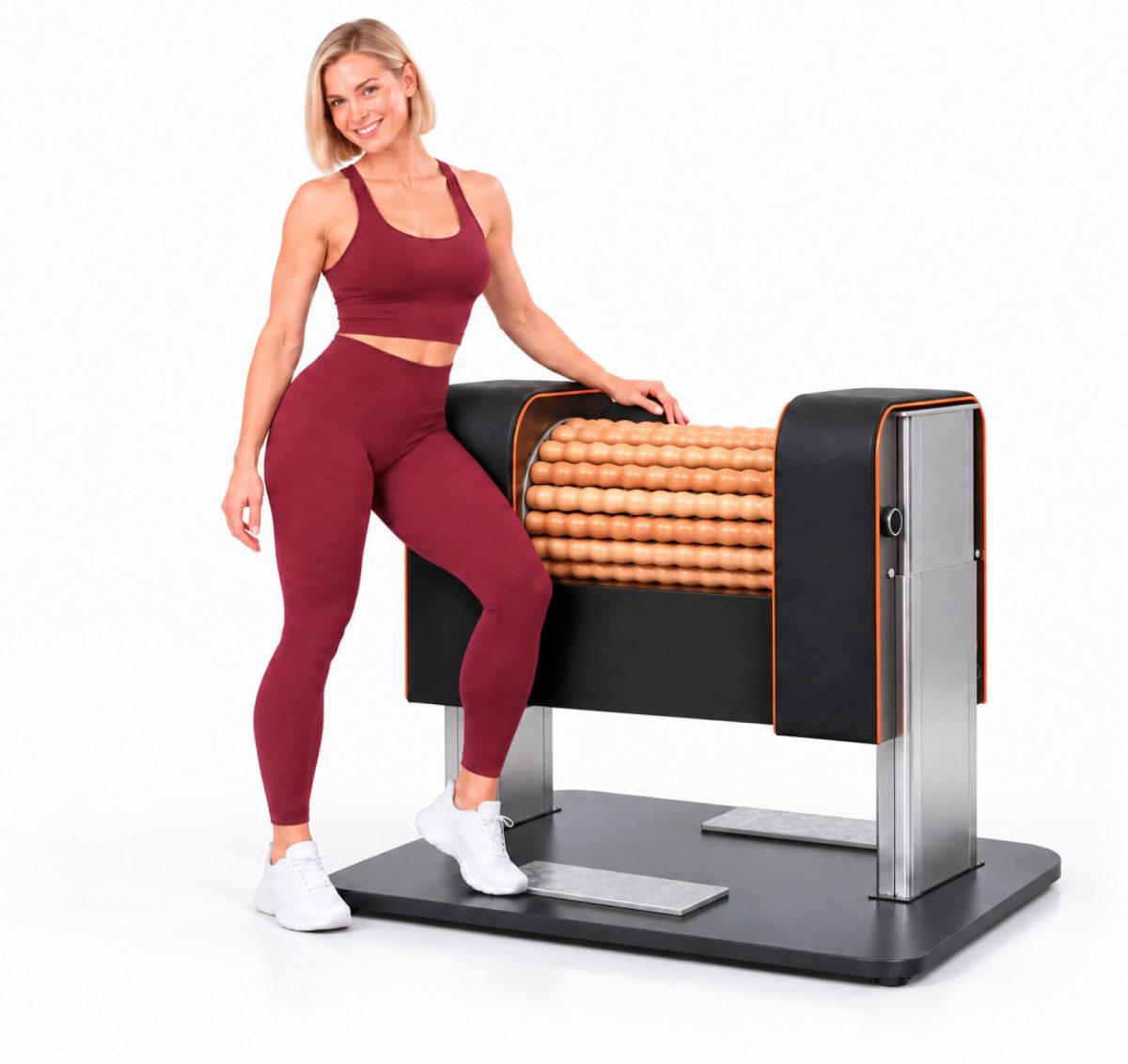 Fit woman in burgundy workout clothes standing beside a large roller massage machine on a platform for leg-muscle therapy inside a studio setting.